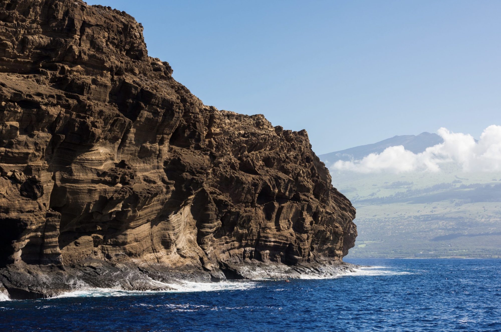 Molokini Crater in Maui a large body of water with a mountain in the background