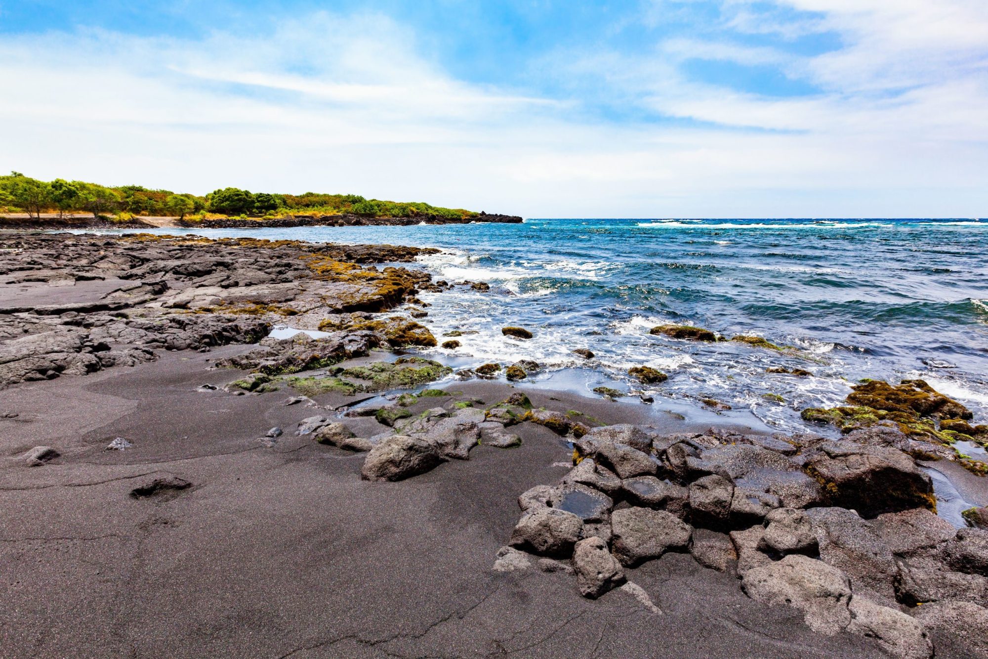 Punaluʻu Beach a rocky beach next to a body of water