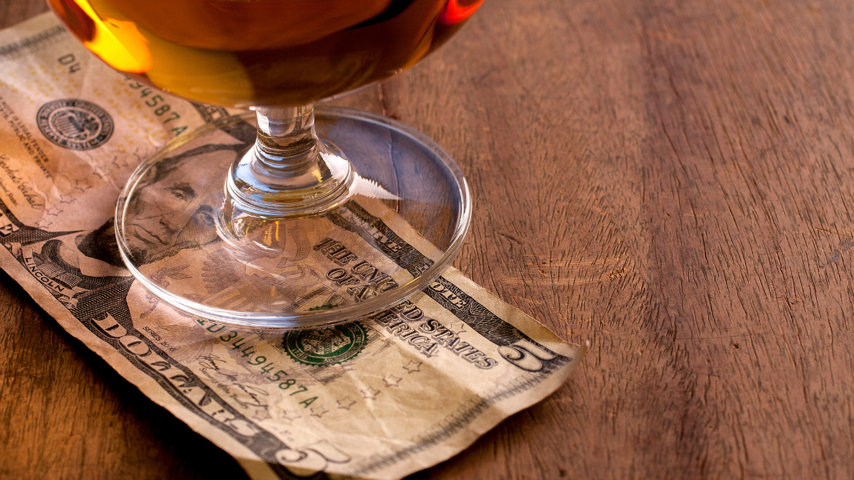 tipping in hawaii a glass of wine sitting on top of a wooden table