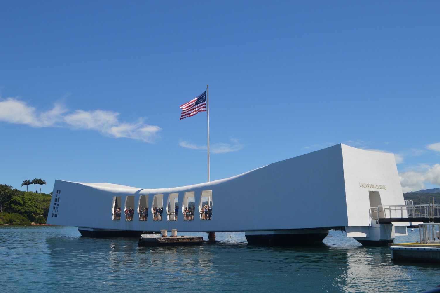 a large ship in a body of water with USS Arizona Memorial in the background