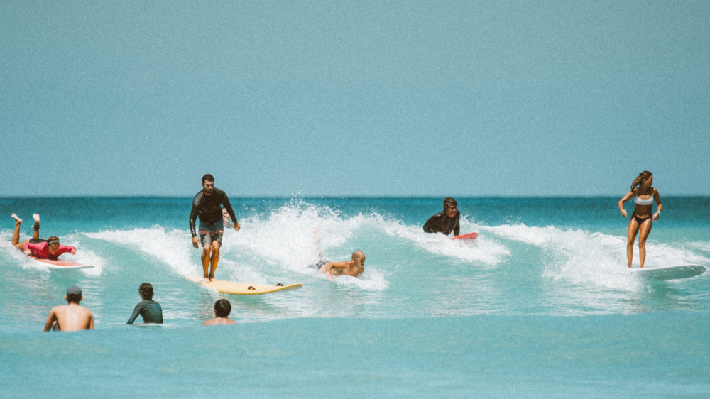 a group of people riding a wave on a surfboard in the water