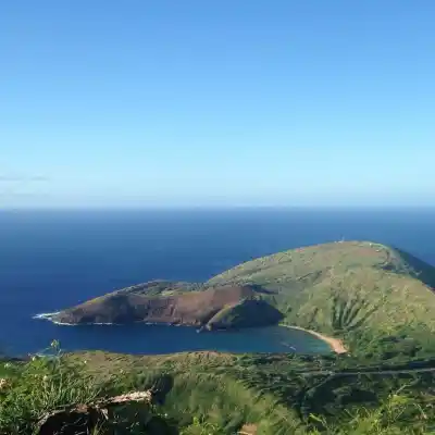 Scenic view of a coastal bay surrounded by green hills under a clear blue sky.