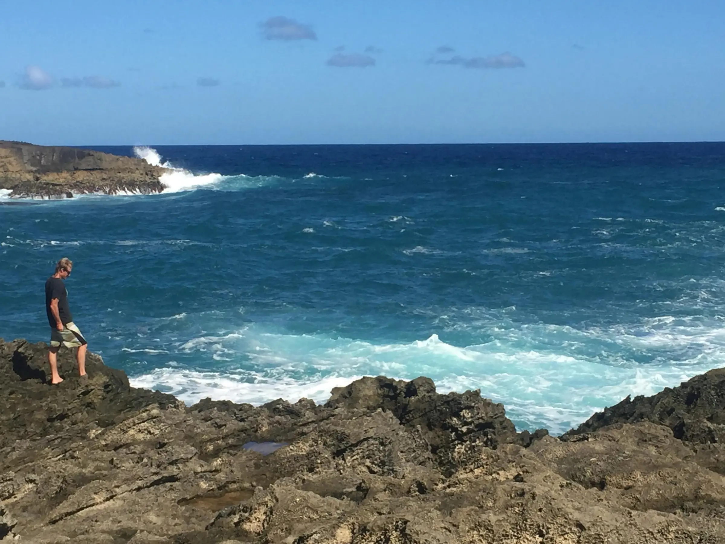 a man standing on a rocky beach next to the ocean