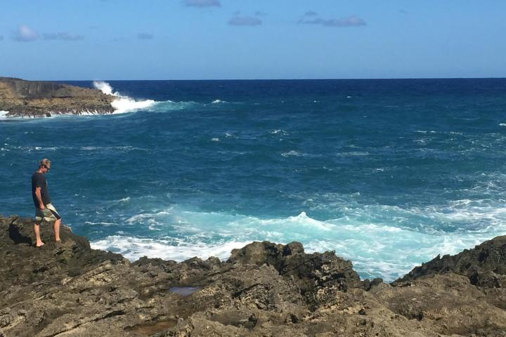 a man standing on a rocky beach next to the ocean
