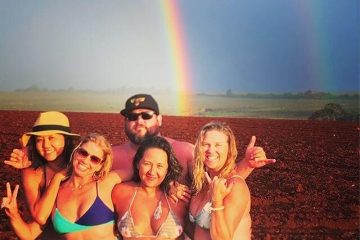 a group of people posing for a picture with a rainbow in the background