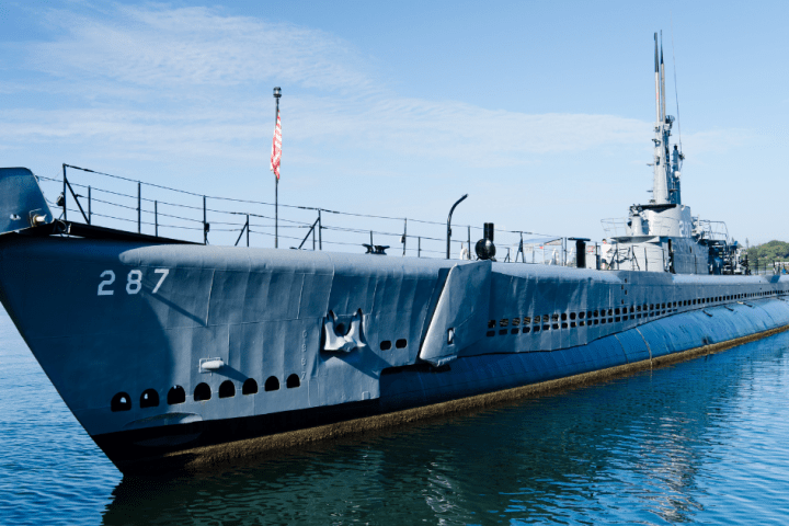 a boat is docked next to a body of water with USS Bowfin (SS-287) in the background